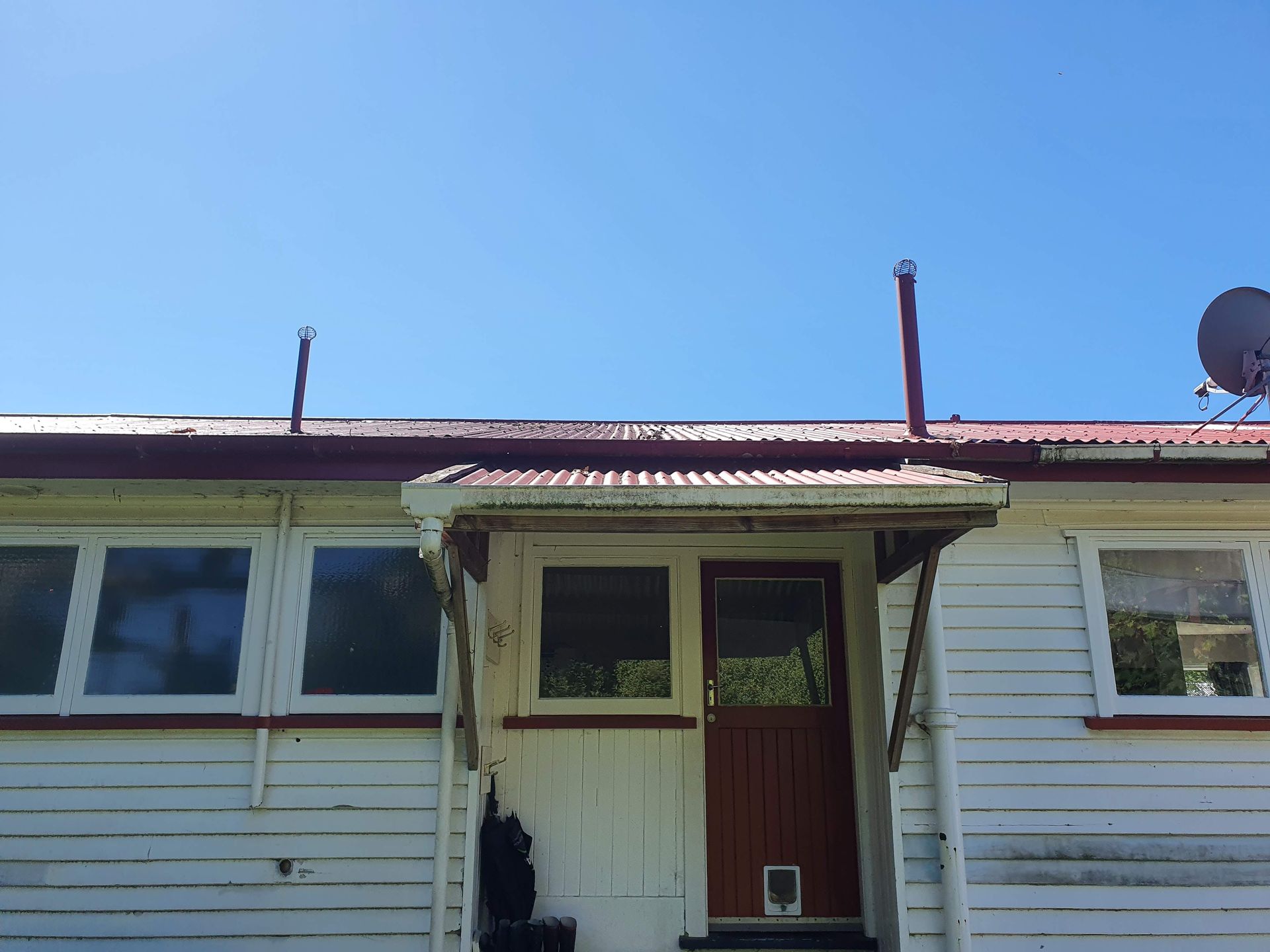 A white house with a red roof and a satellite dish on the roof