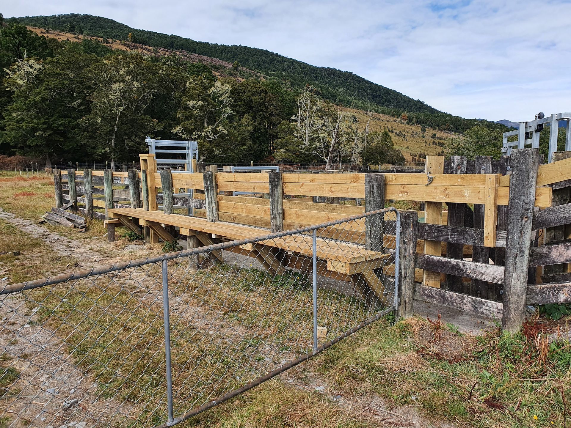 A wooden fence in a field with mountains in the background.