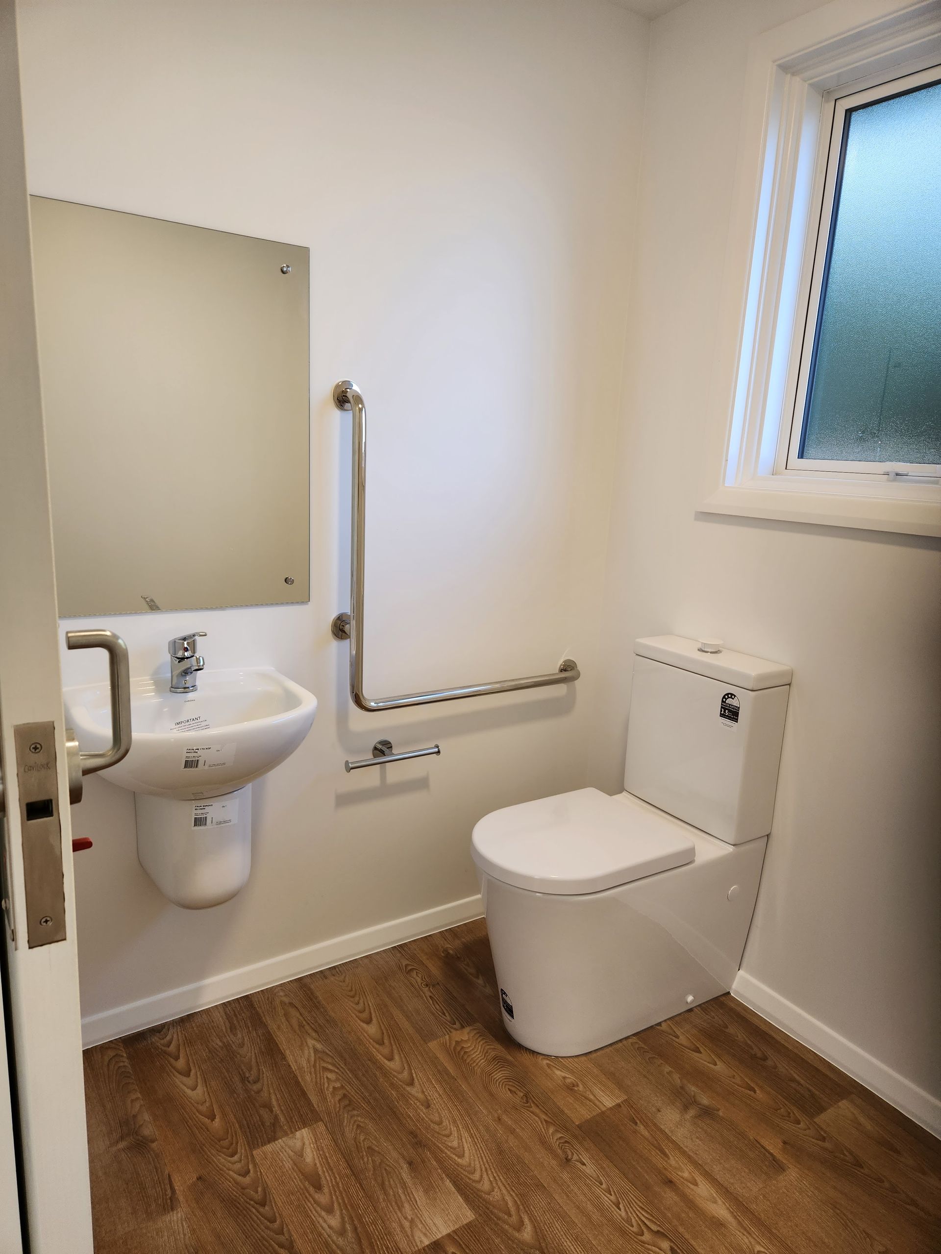 A bathroom with a toilet , sink and mirror.