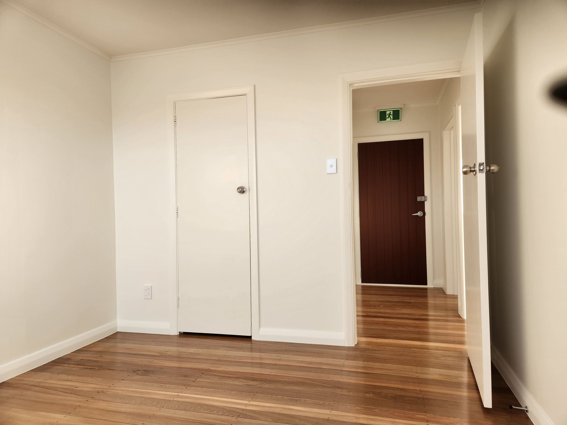 An empty room with hardwood floors and white walls