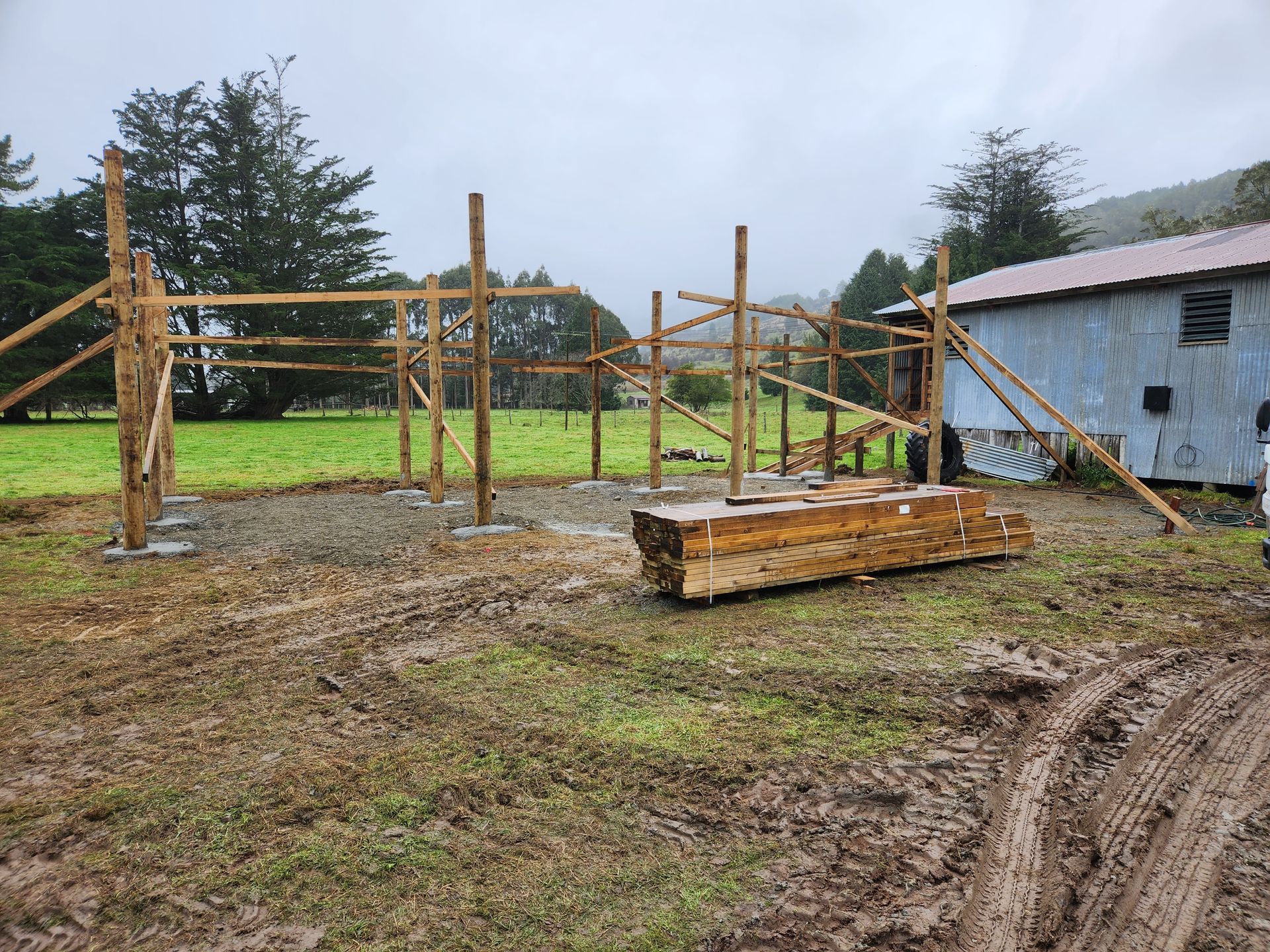 A wooden fence is being built in a muddy field.
