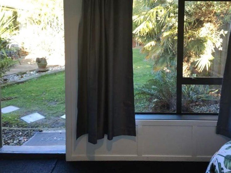 A bedroom with a view of a garden through a window
