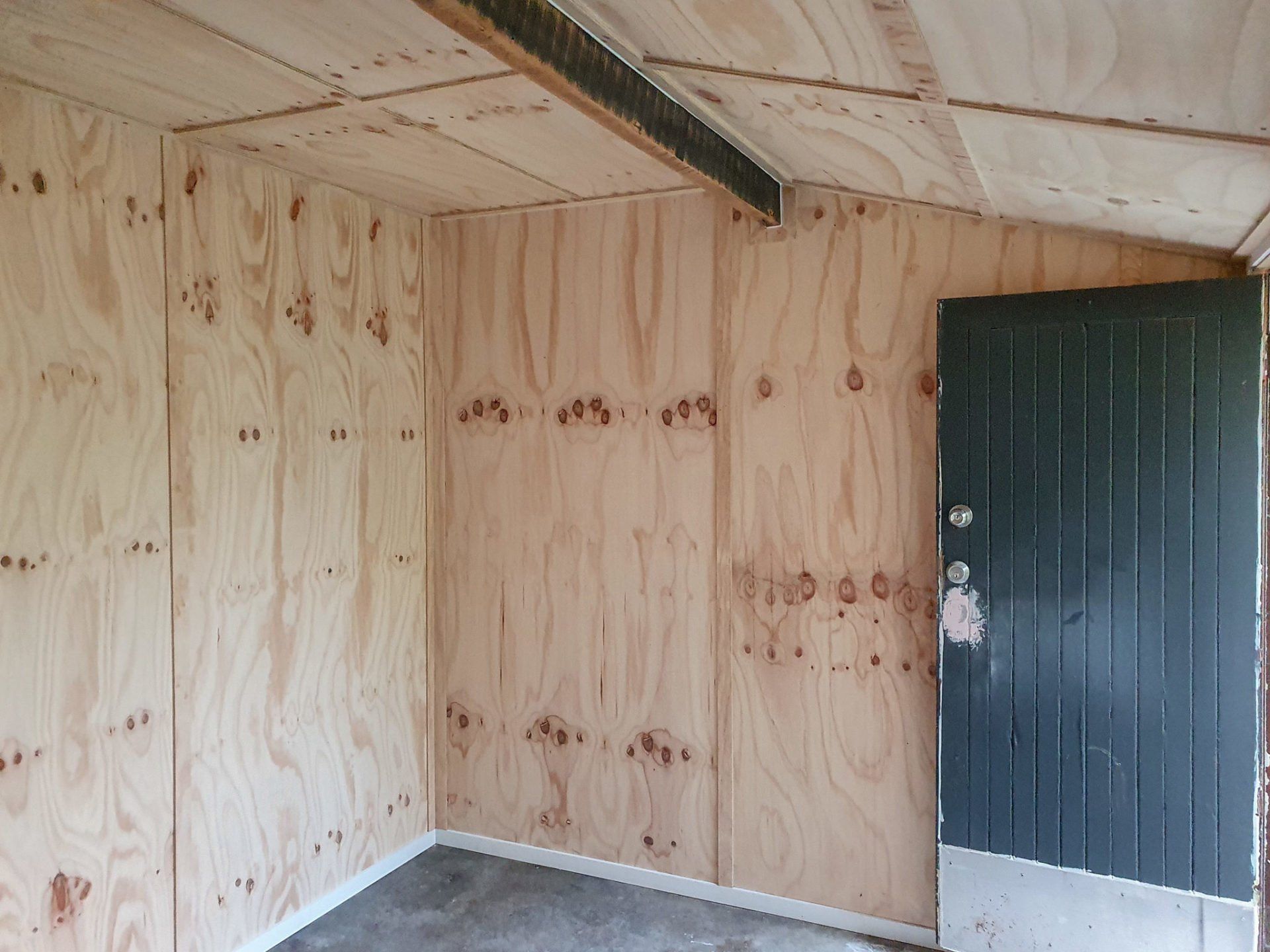 A room with wooden walls and a black door