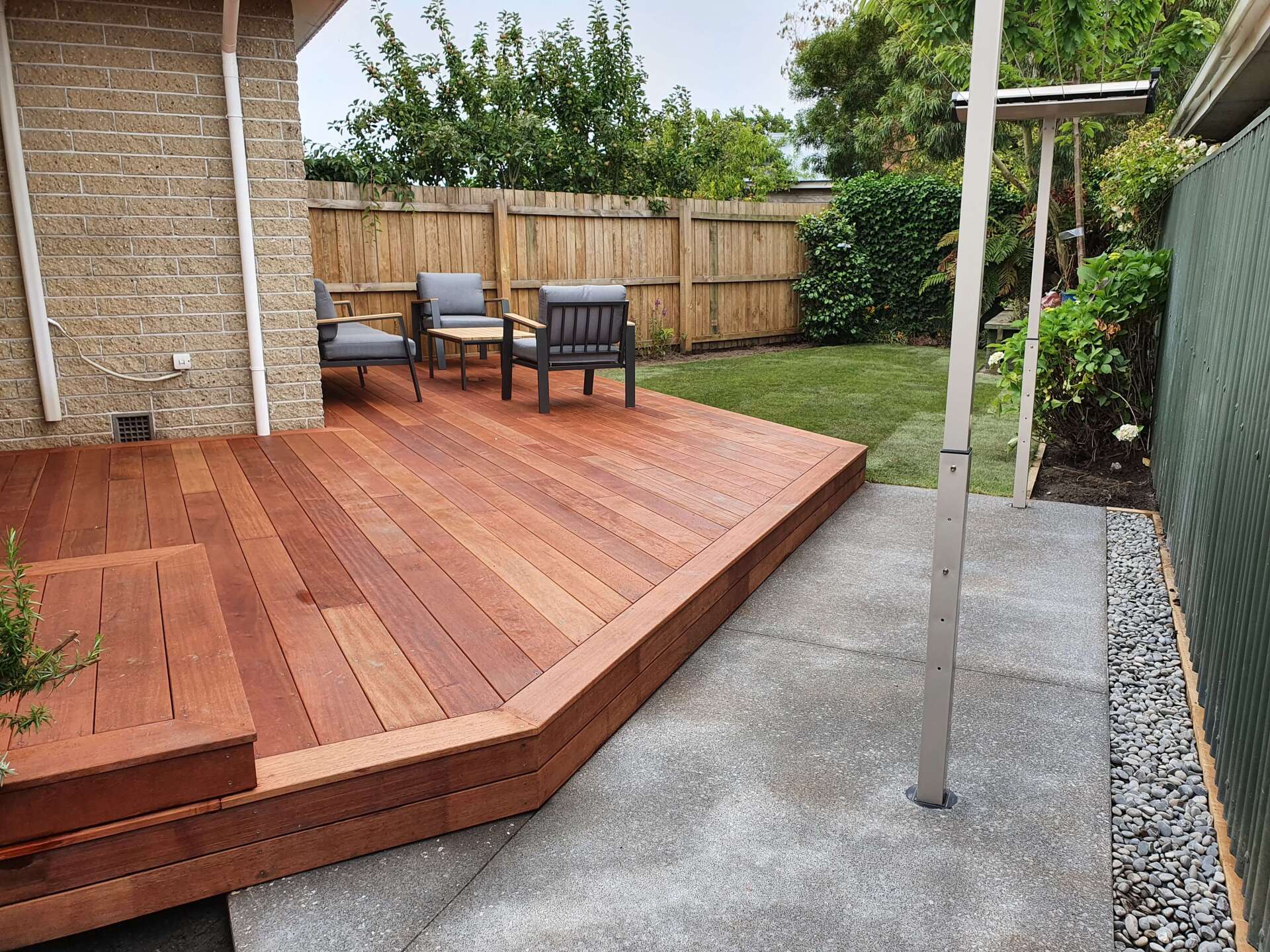 A wooden deck with chairs and a table in a backyard.