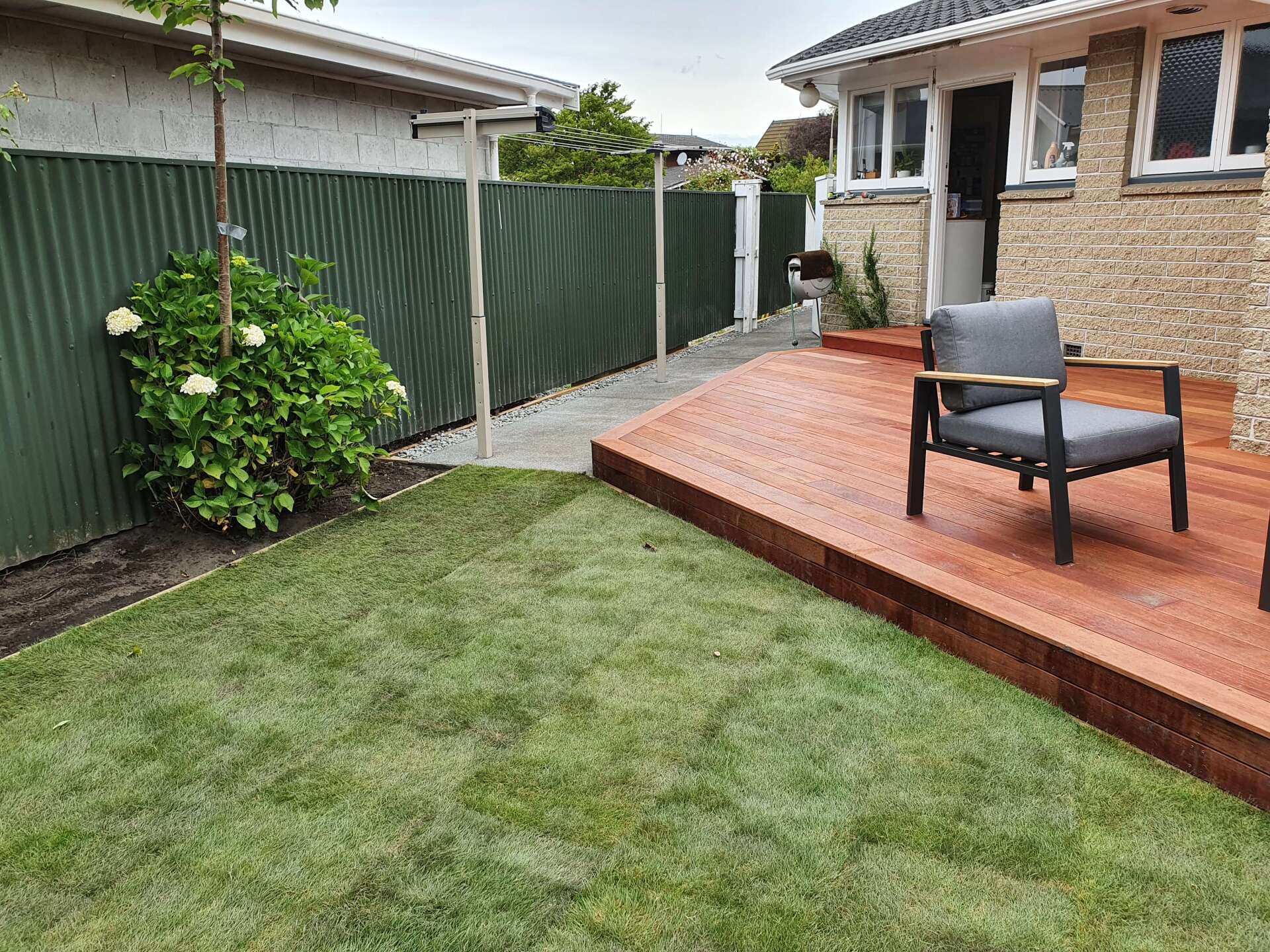 A wooden deck with a chair and a fence in the backyard of a house.