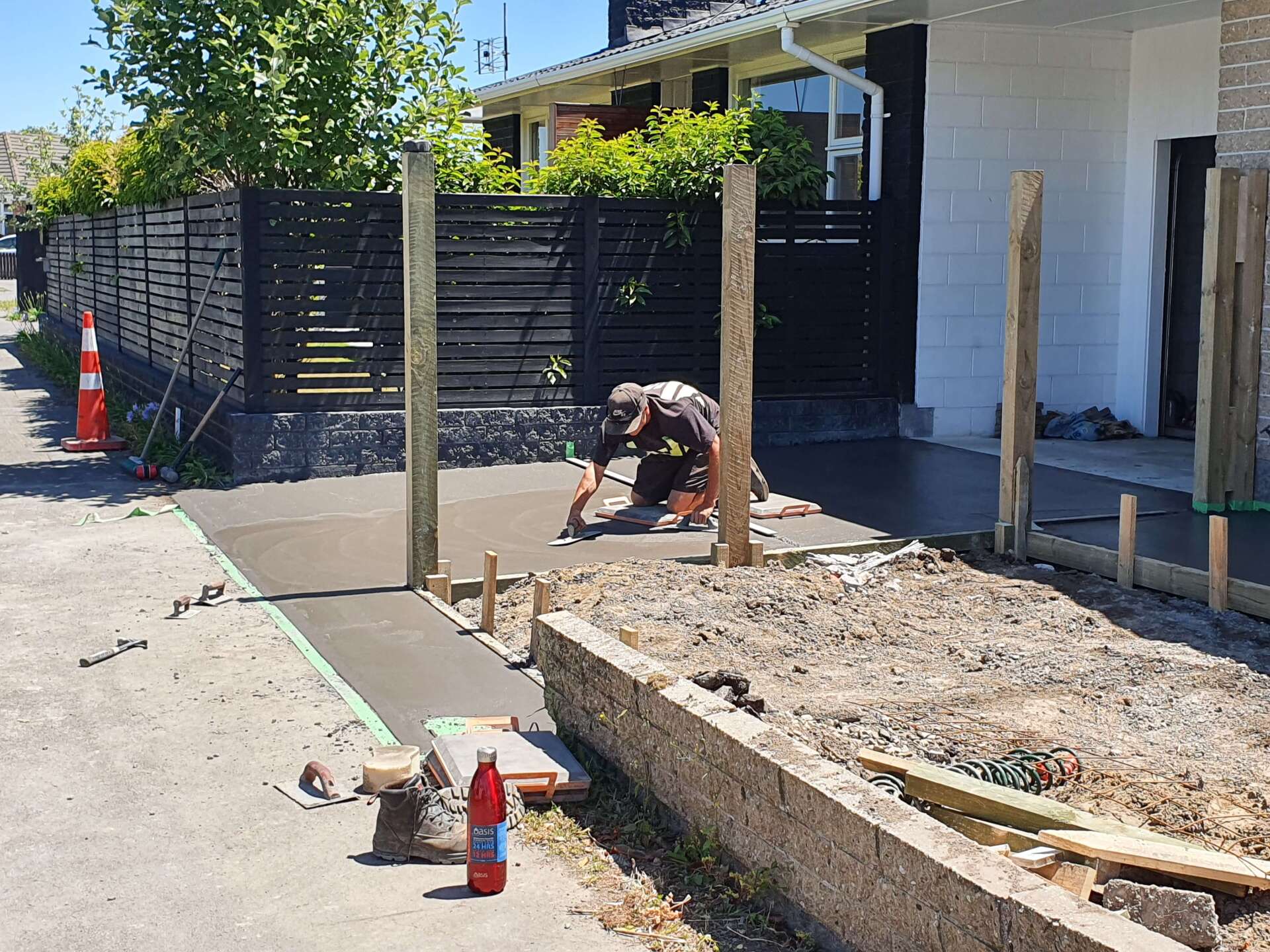 A man is working on a sidewalk in front of a house.