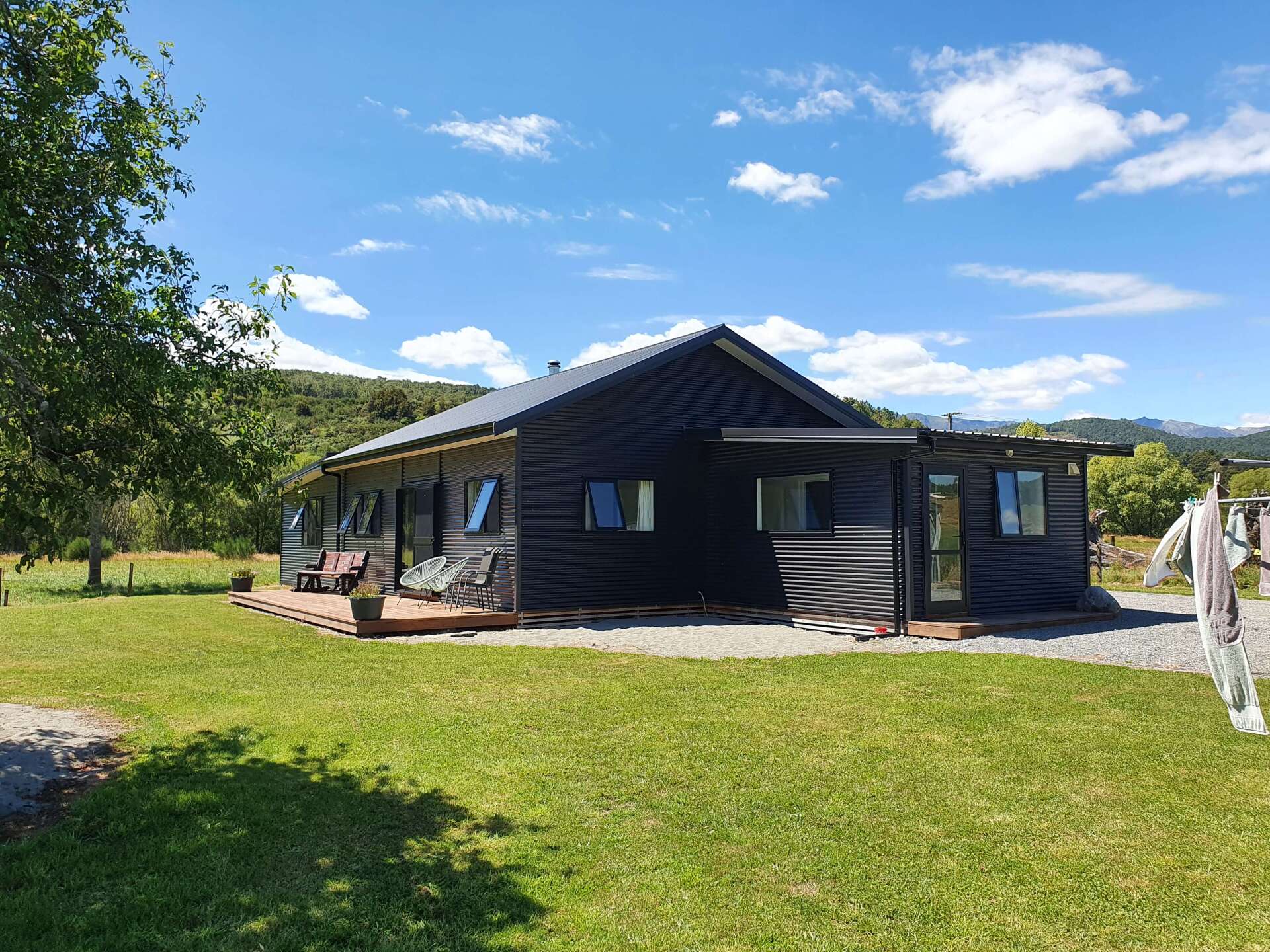 A small black house is sitting in the middle of a lush green field.