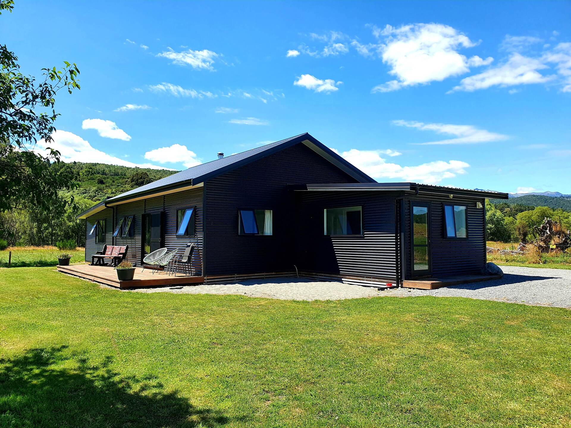 A black house is sitting in the middle of a lush green field.