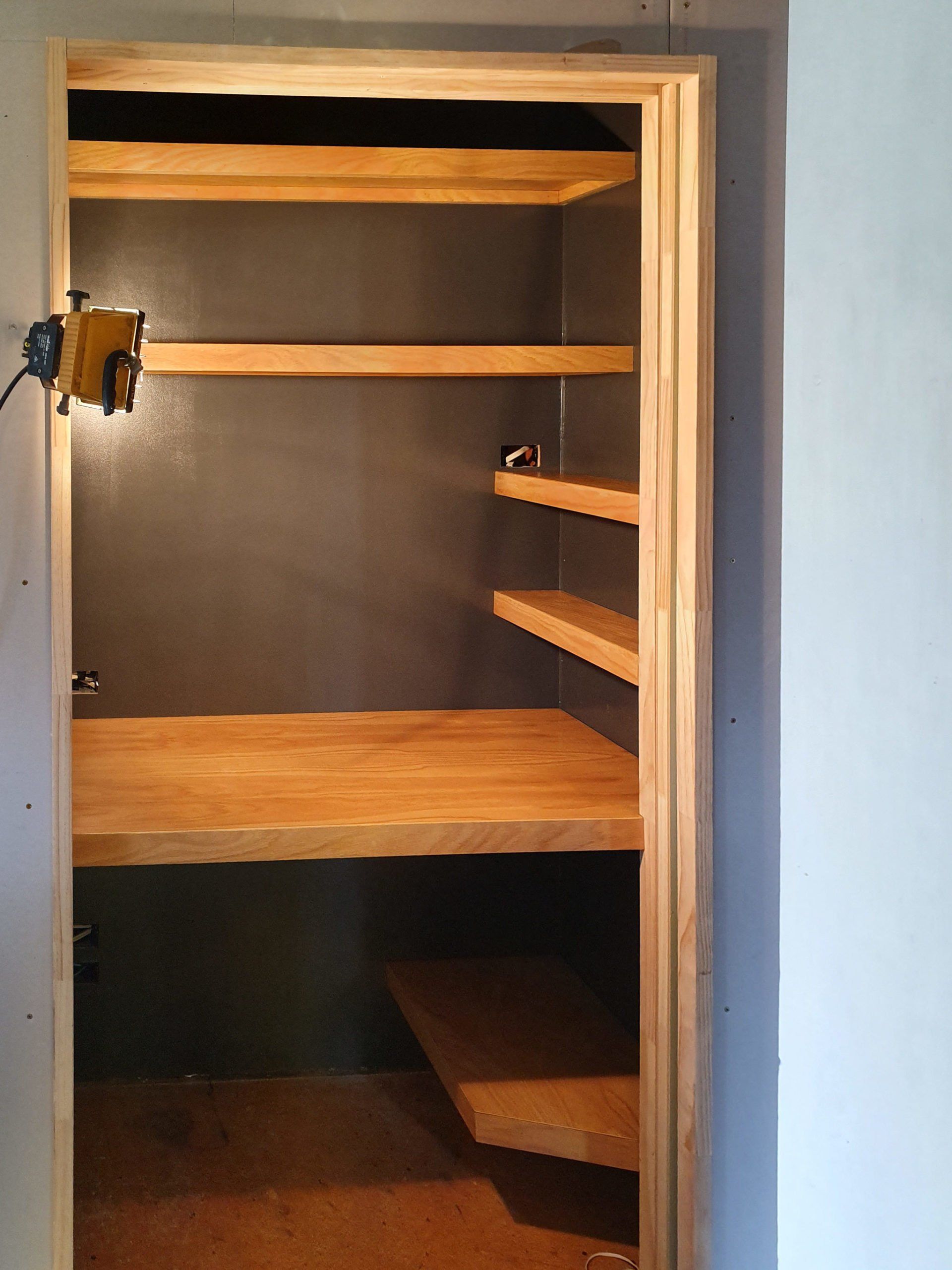 A closet with wooden shelves and a wooden table