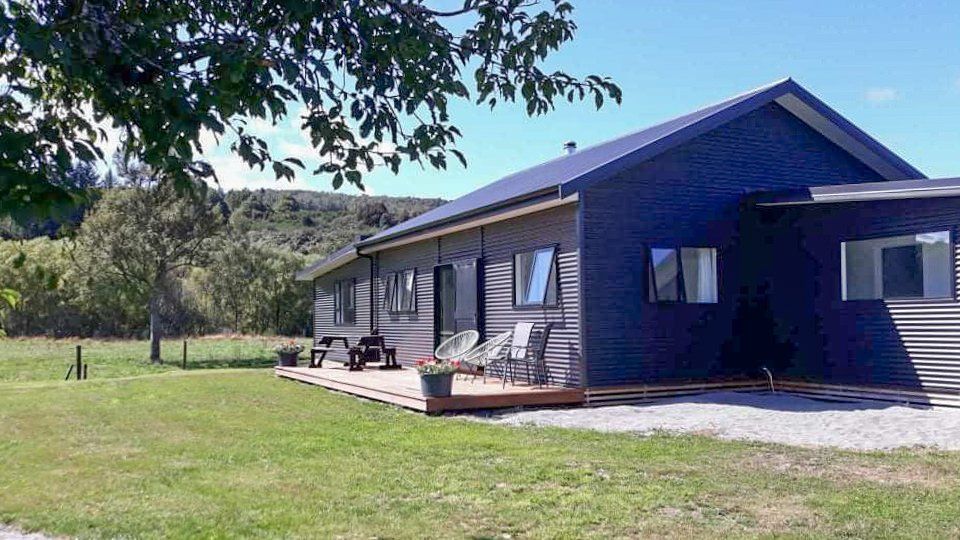 A large house with a deck in the middle of a grassy field.