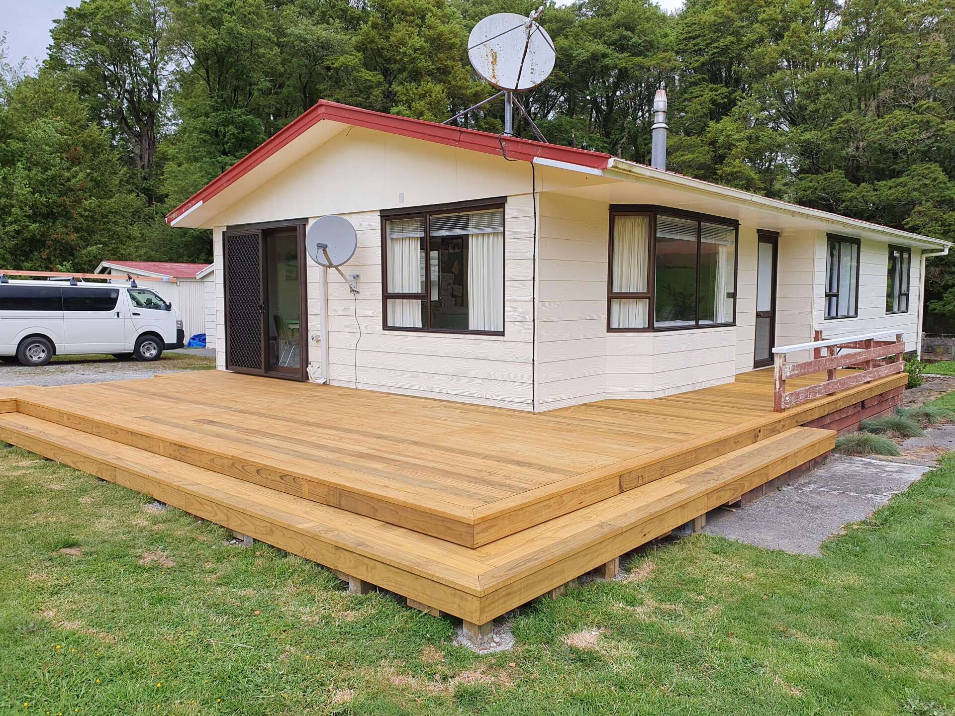 A small white house with a wooden deck in front of it.