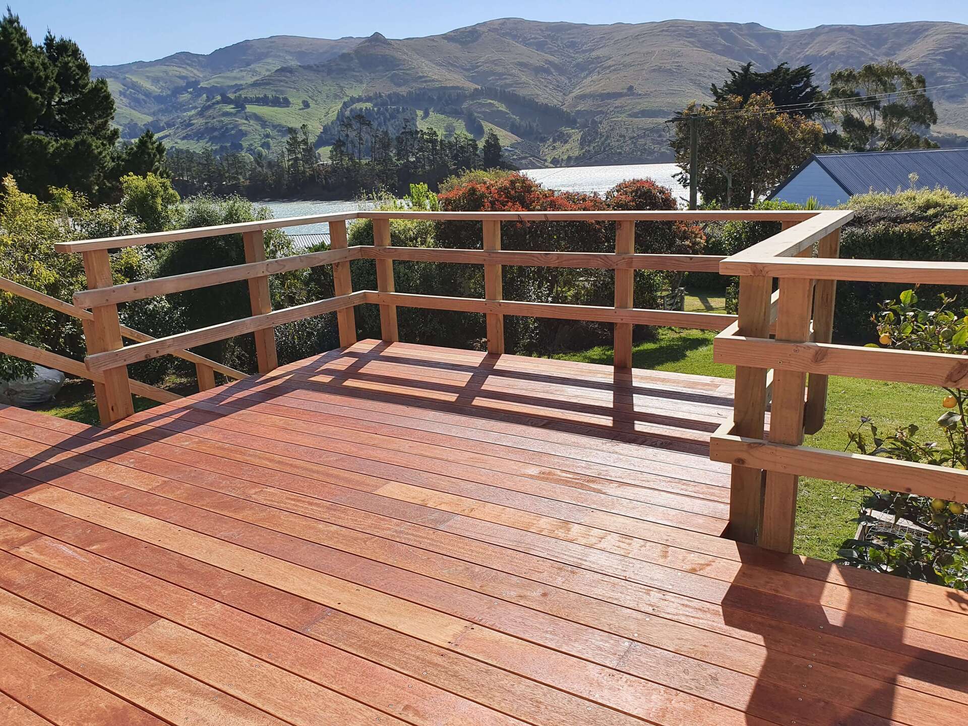 A wooden deck with a fence and mountains in the background