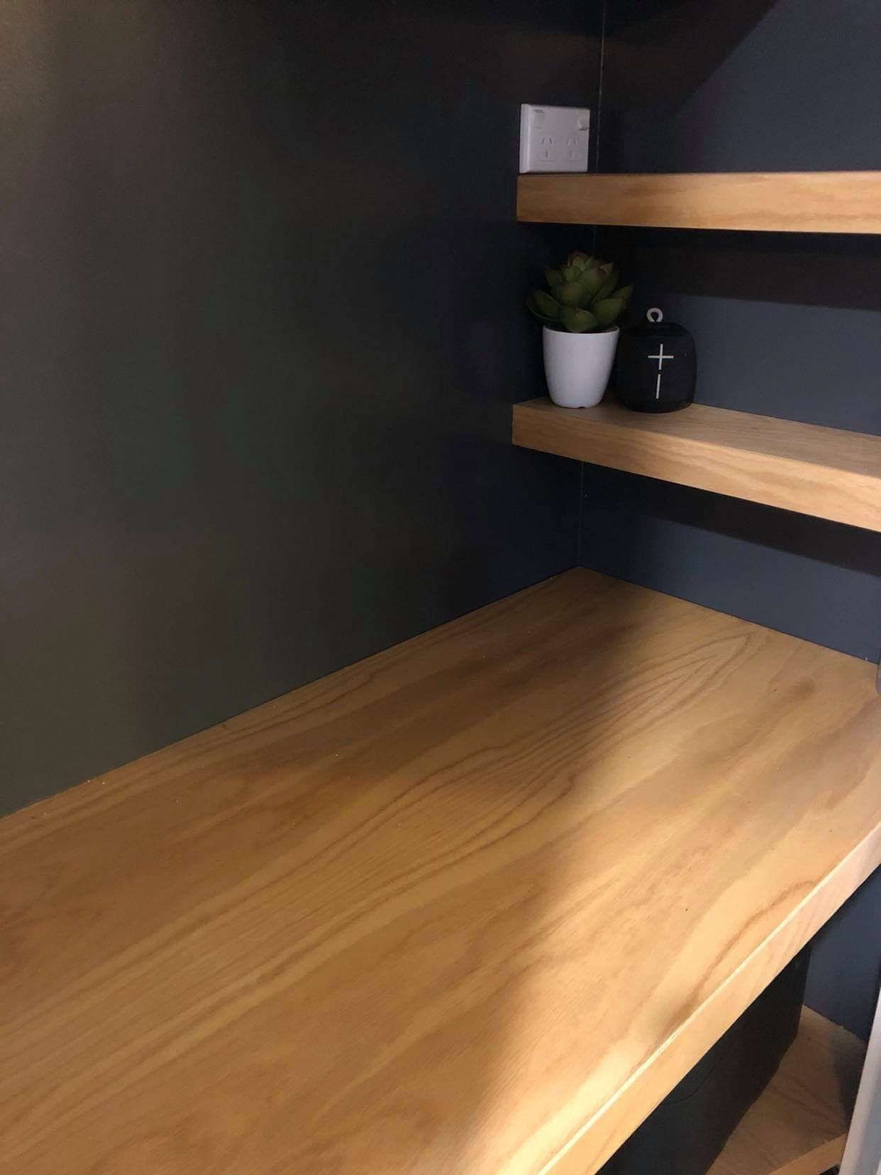 A wooden desk with shelves and a plant on it