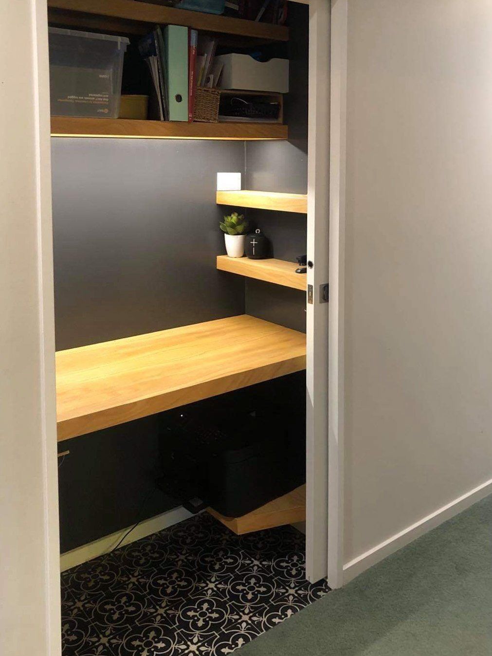 A closet with a wooden desk and shelves in it