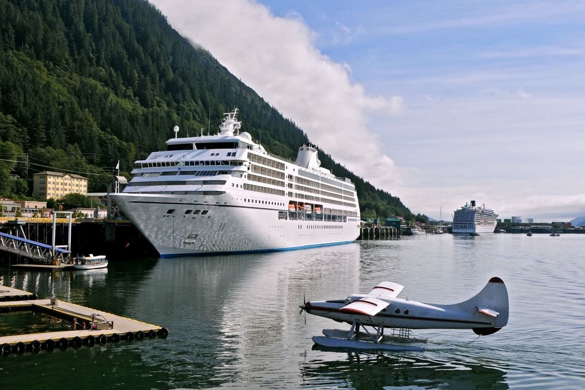 A cruise ship is docked next to a seaplane in the water.