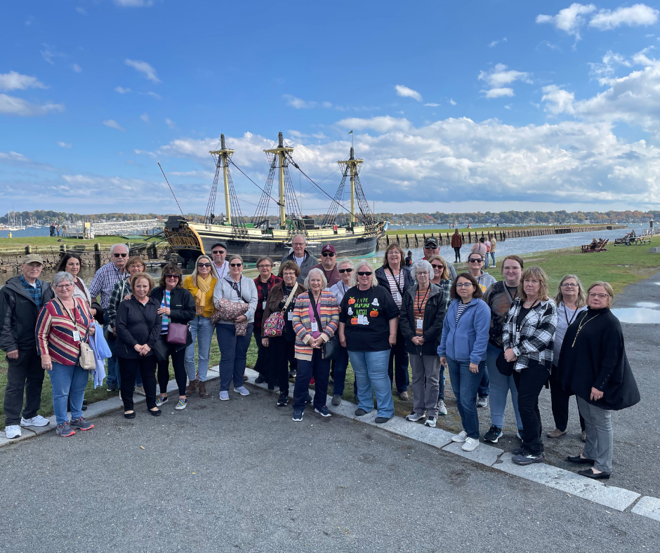 A group of people are posing for a picture in front of a ship.