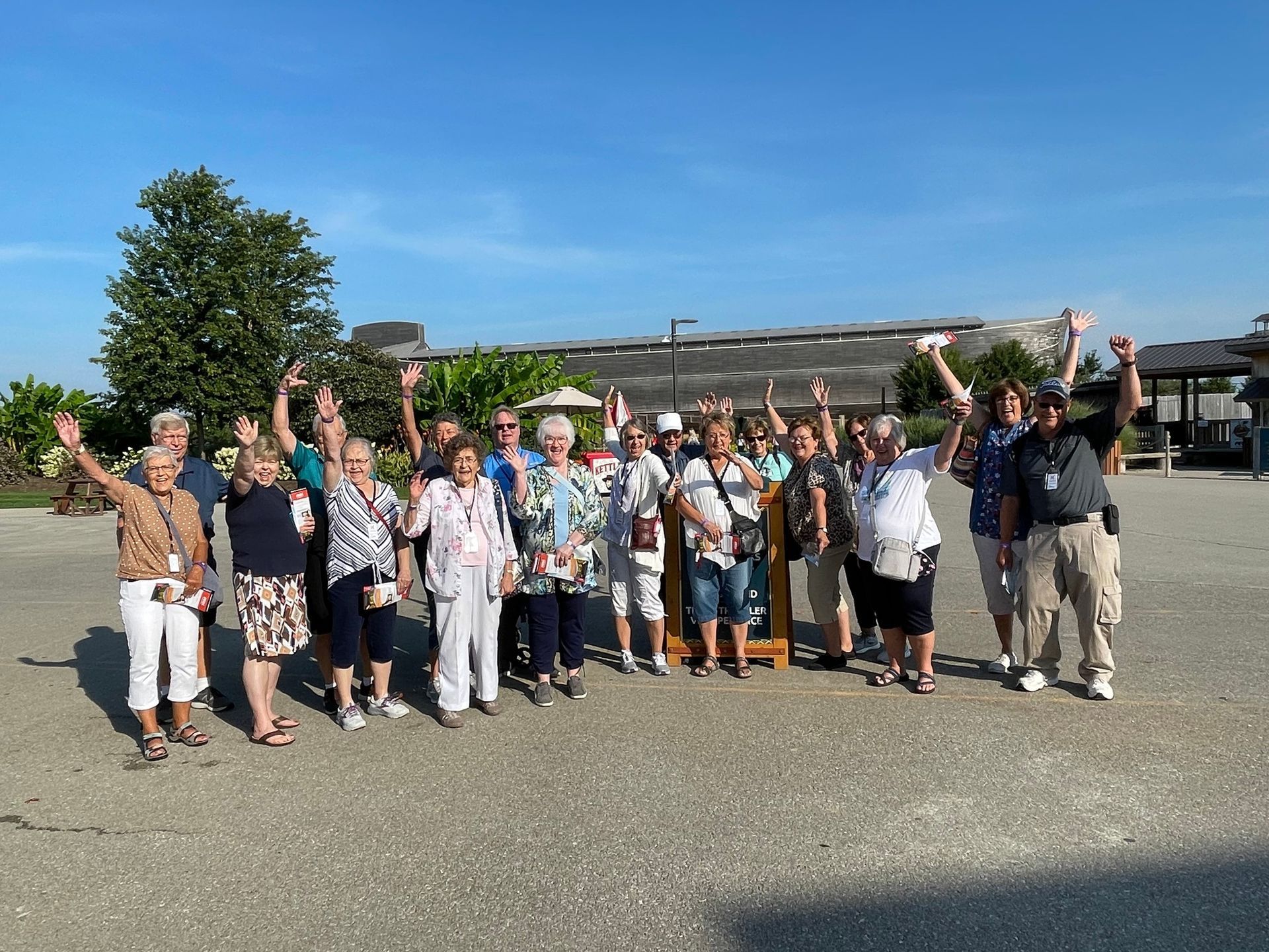 A group of people are standing in a parking lot with their arms in the air.