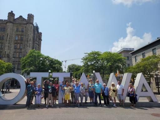A group of people standing in front of a large ottawa sign