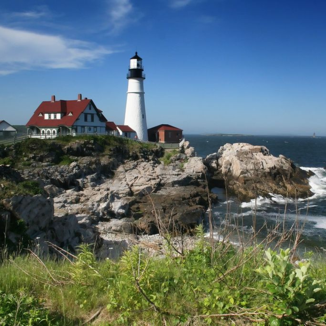 A lighthouse sits on a rocky cliff overlooking the ocean