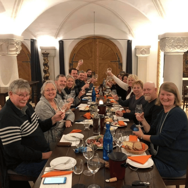 A group of people toasting at a long table in a stone-walled room.