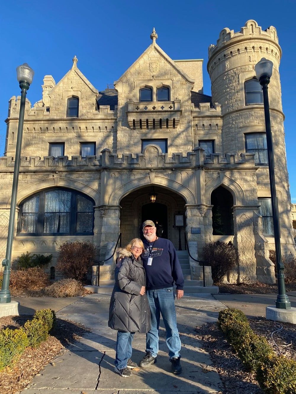 A man and a woman are standing in front of a castle.