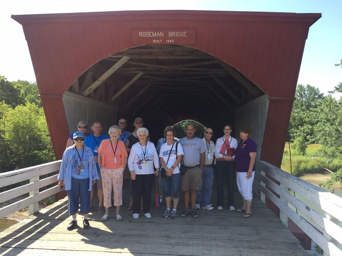 A group of people are posing for a picture in front of a covered bridge.