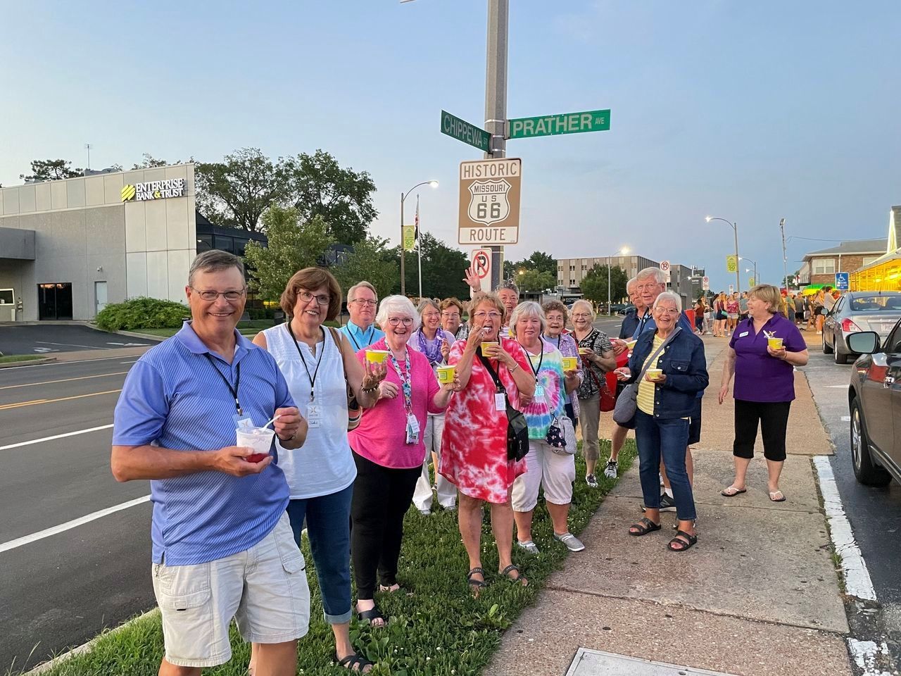 A group of people are standing on the side of the road holding ice cream cones.