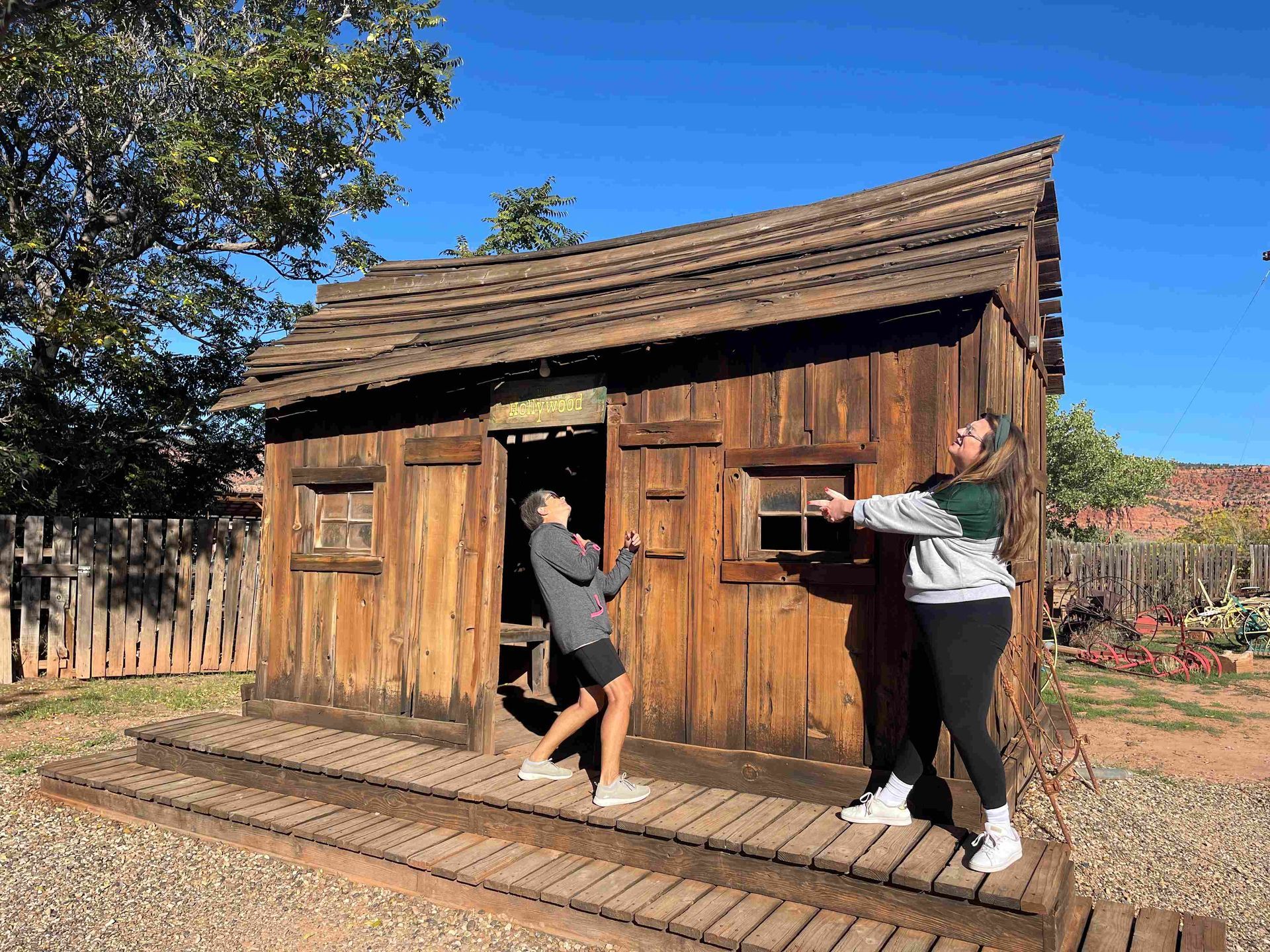 Two women are standing in front of a wooden house.