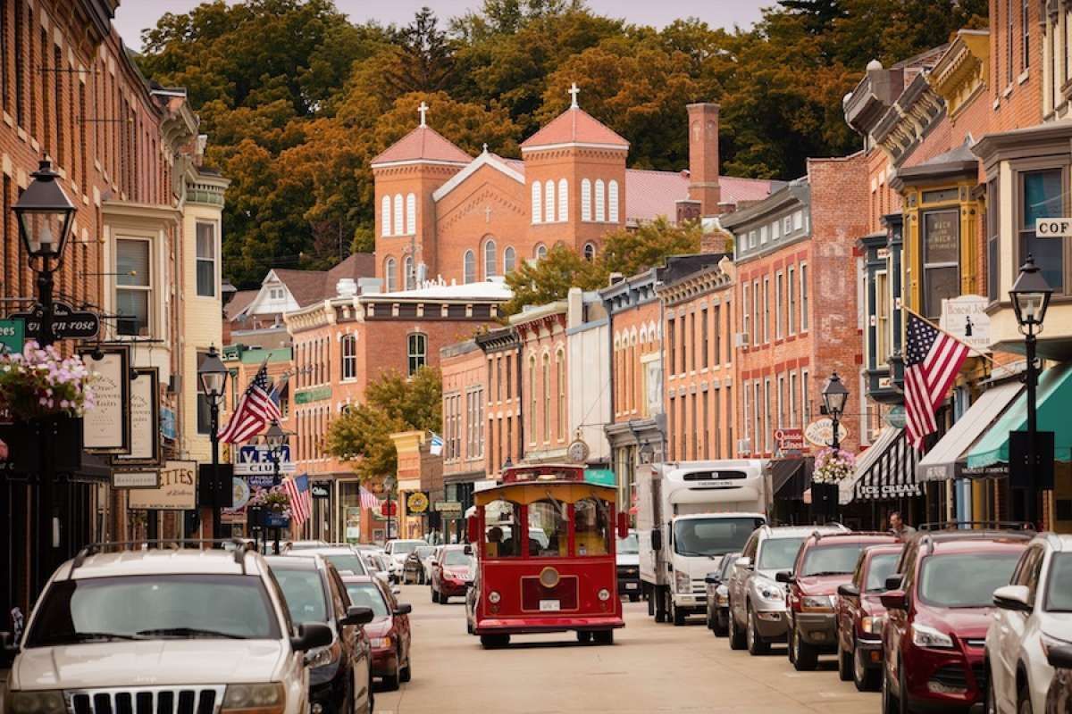 A red trolley is driving down a busy city street.
