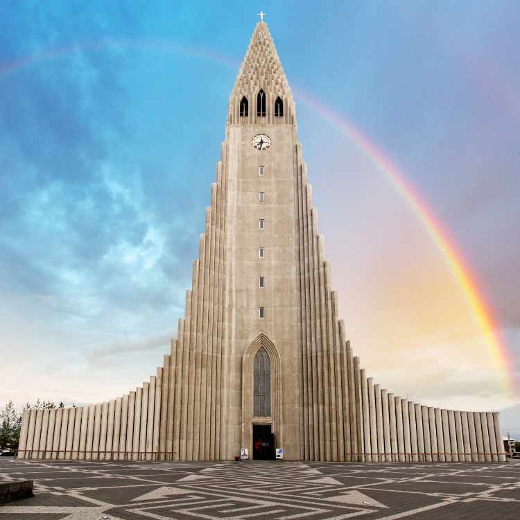 A large building with a clock tower and a rainbow in the background.