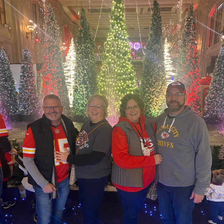 A group of people are posing for a picture in front of christmas trees.