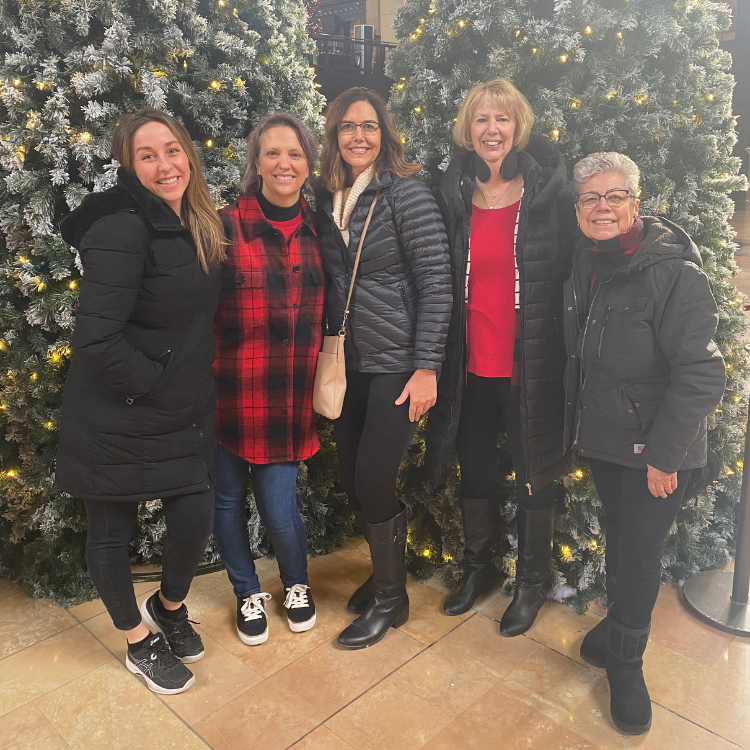 A group of women standing in front of a christmas tree