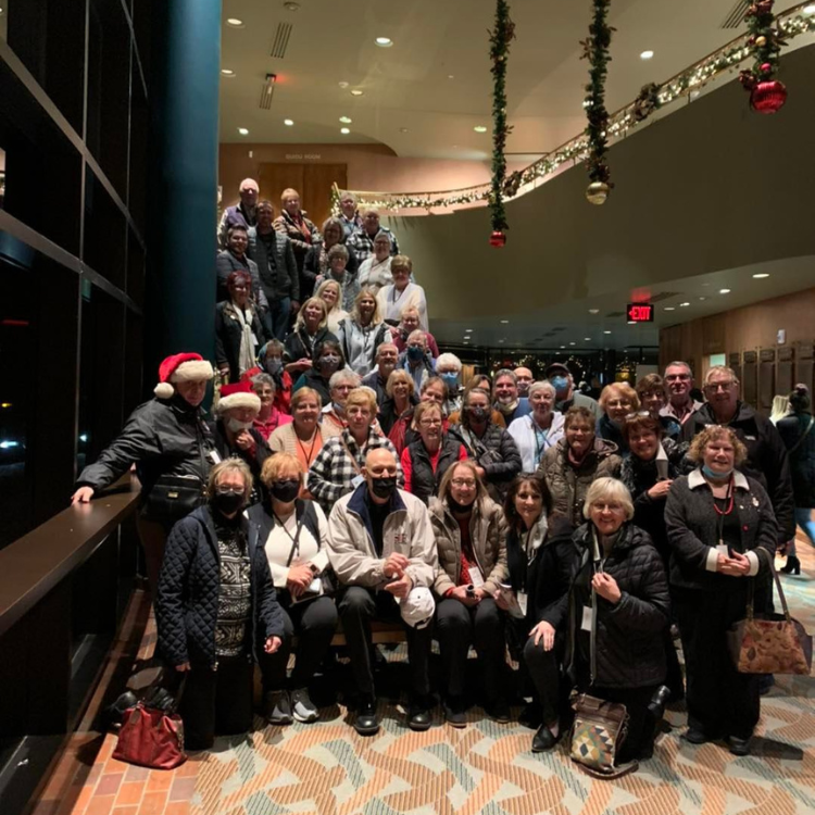 Large group of people, many wearing holiday attire, inside a building.