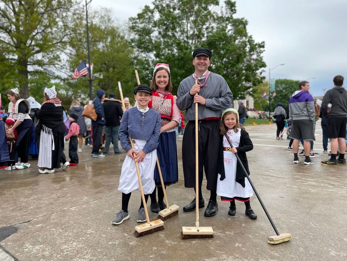 A family is posing for a picture with brooms in front of a crowd.