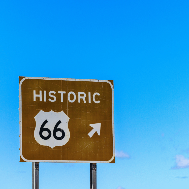 Historic Route 66 sign against a bright blue sky.