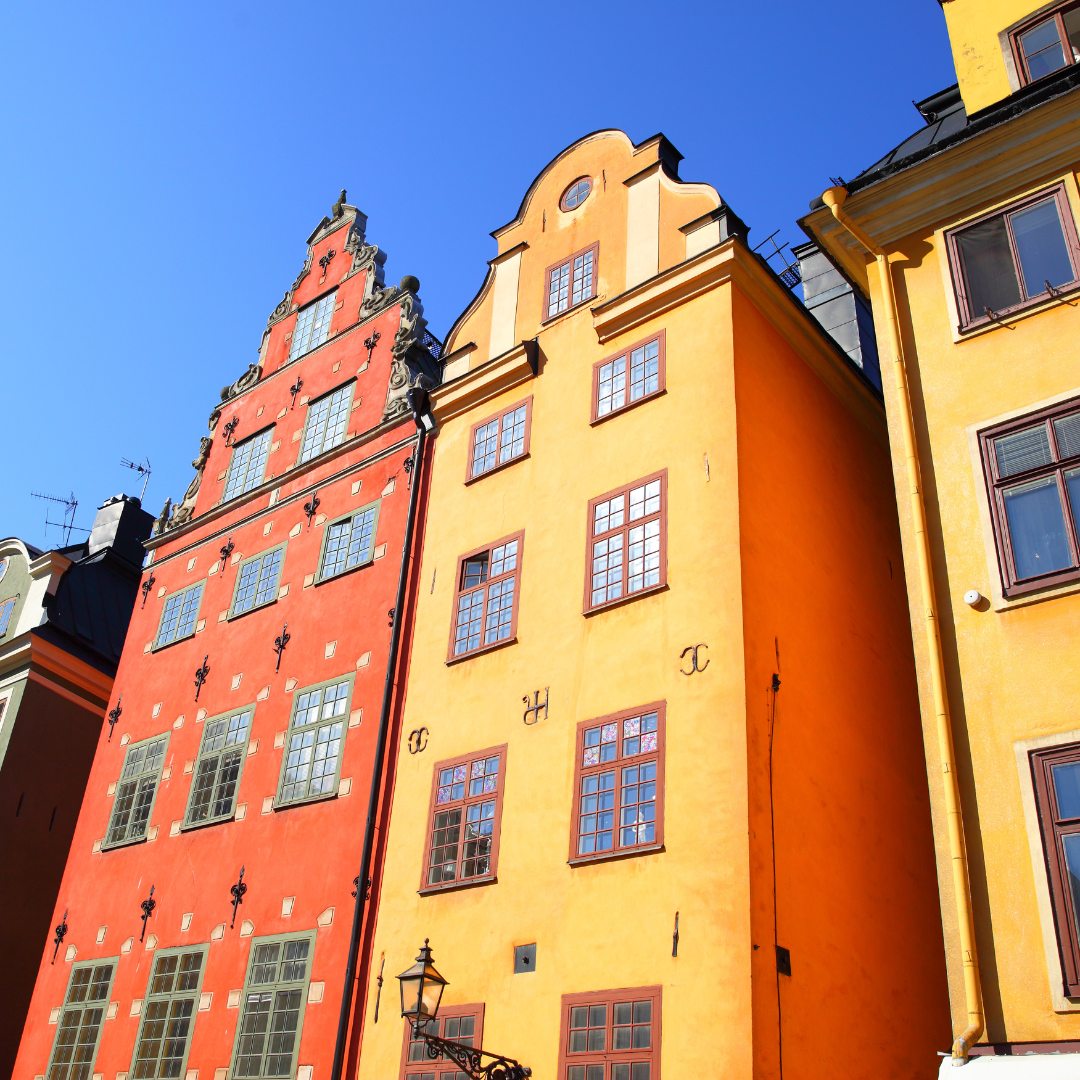 Colorful buildings in Stockholm with orange and yellow facades against a blue sky.