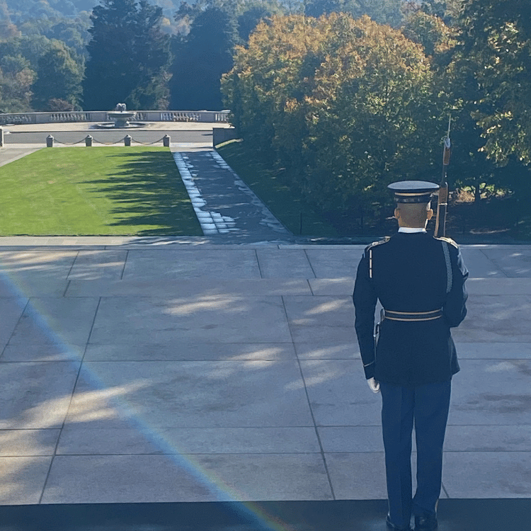 Soldier stands at attention at Arlington National Cemetery, holding a rifle.