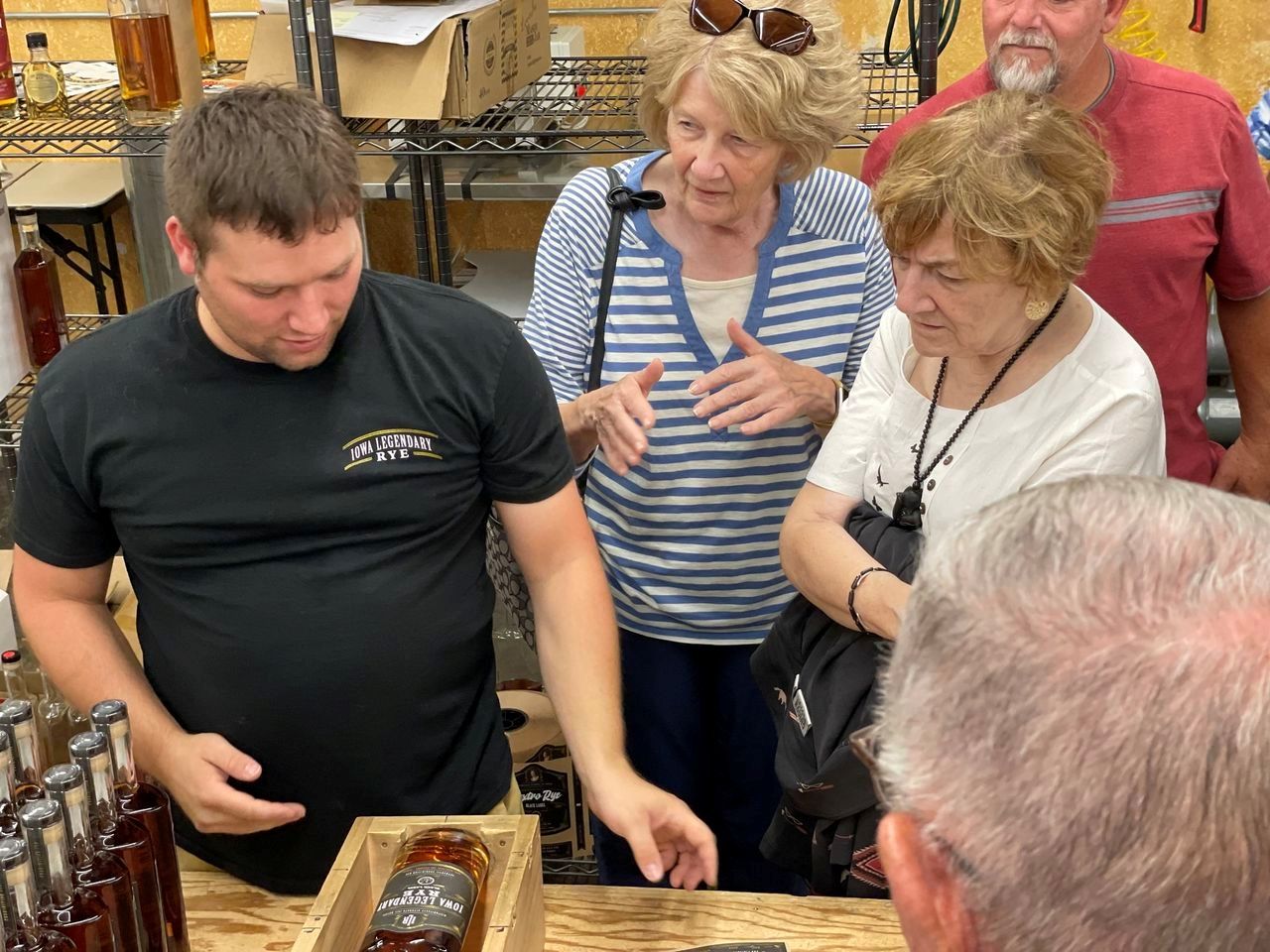 A group of people are looking at a bottle of whiskey
