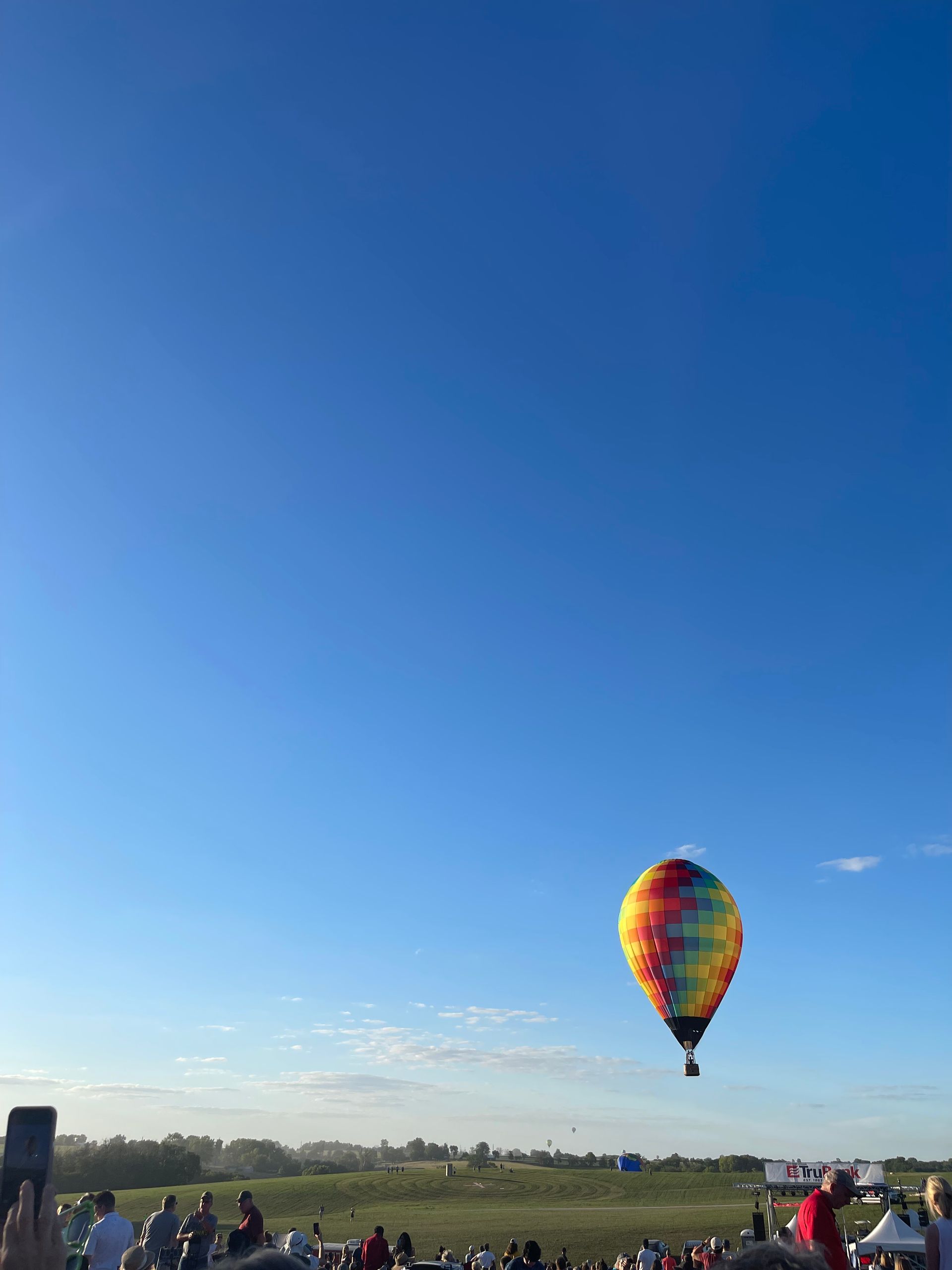 A colorful hot air balloon is flying over a field
