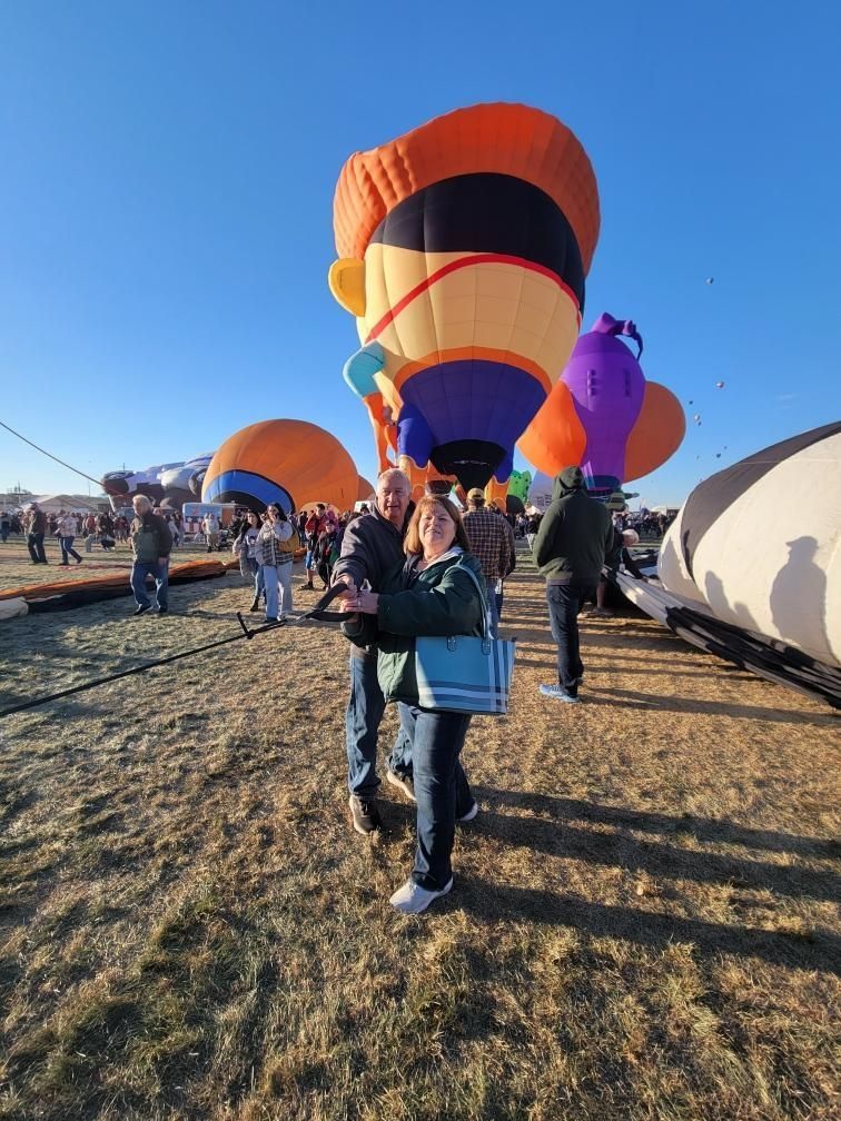 A man and a woman are standing in front of a hot air balloon.