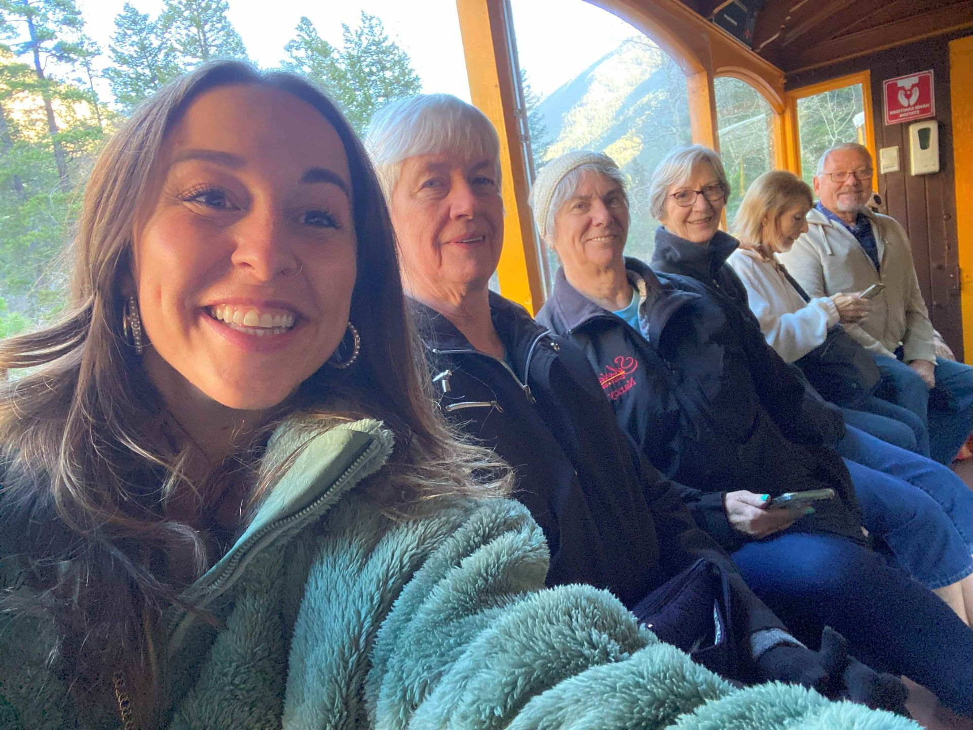 A woman is taking a selfie with a group of people on a train.