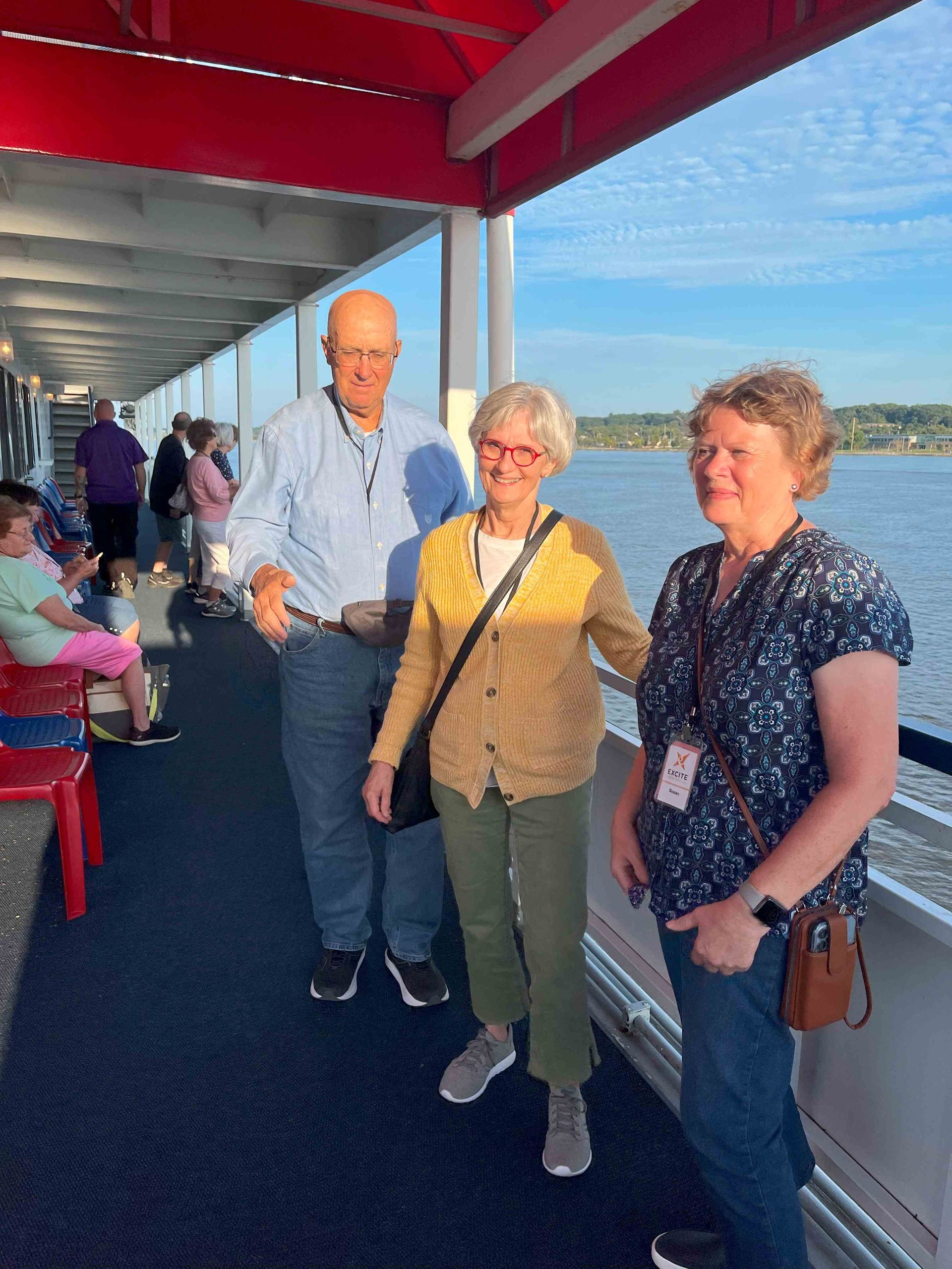 A man and two women are standing on the deck of a boat
