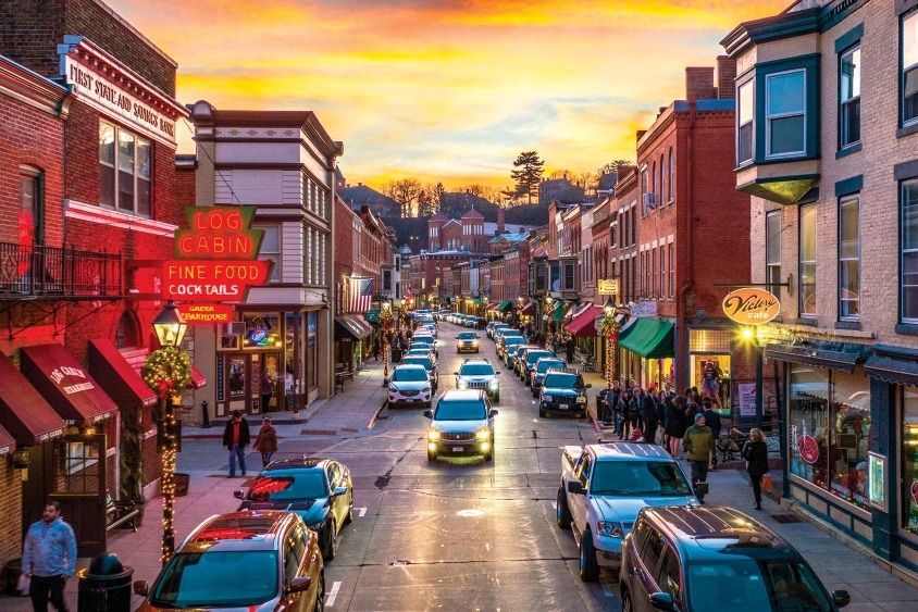 A busy city street with a lot of cars driving down it at sunset.