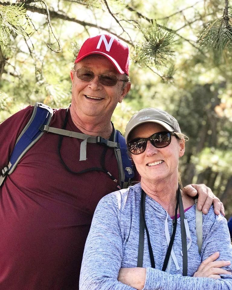 A man and a woman are posing for a picture in the woods.