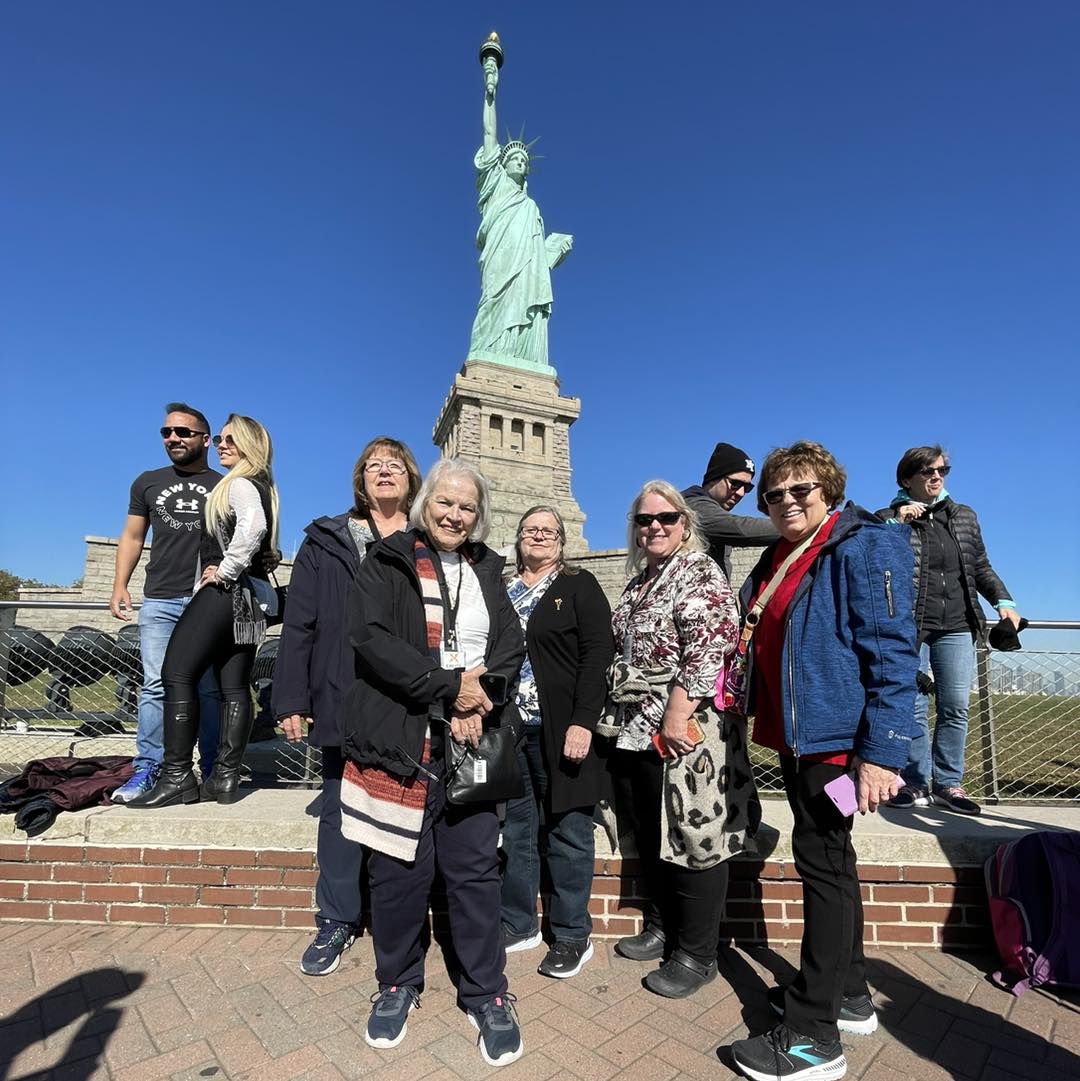 A group of people standing in front of the statue of liberty