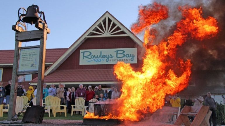 A group of people are gathered in front of rowley 's bay