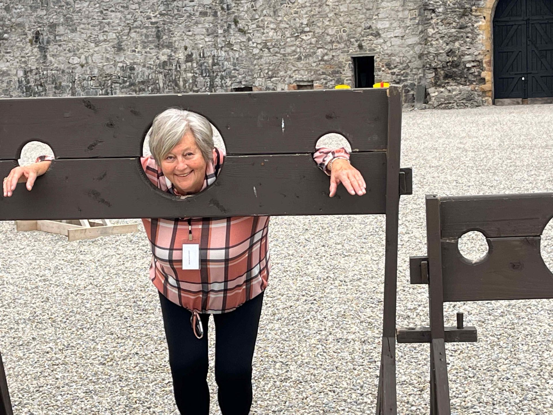 A woman is standing in front of a wooden stockade.