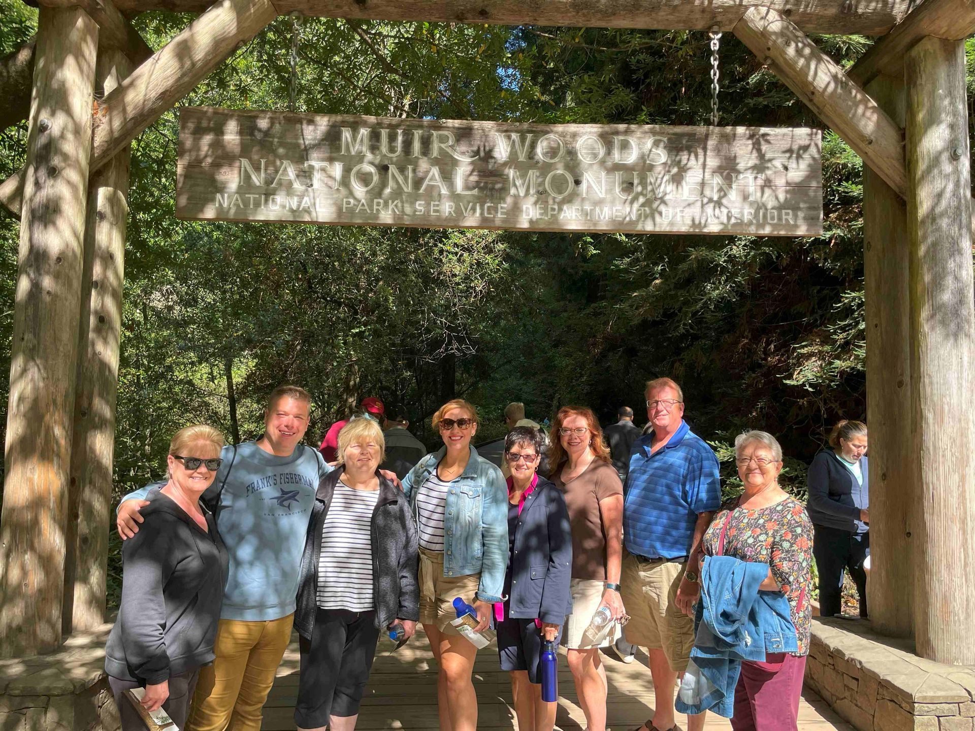 A group of people are posing for a picture in front of a wooden sign.