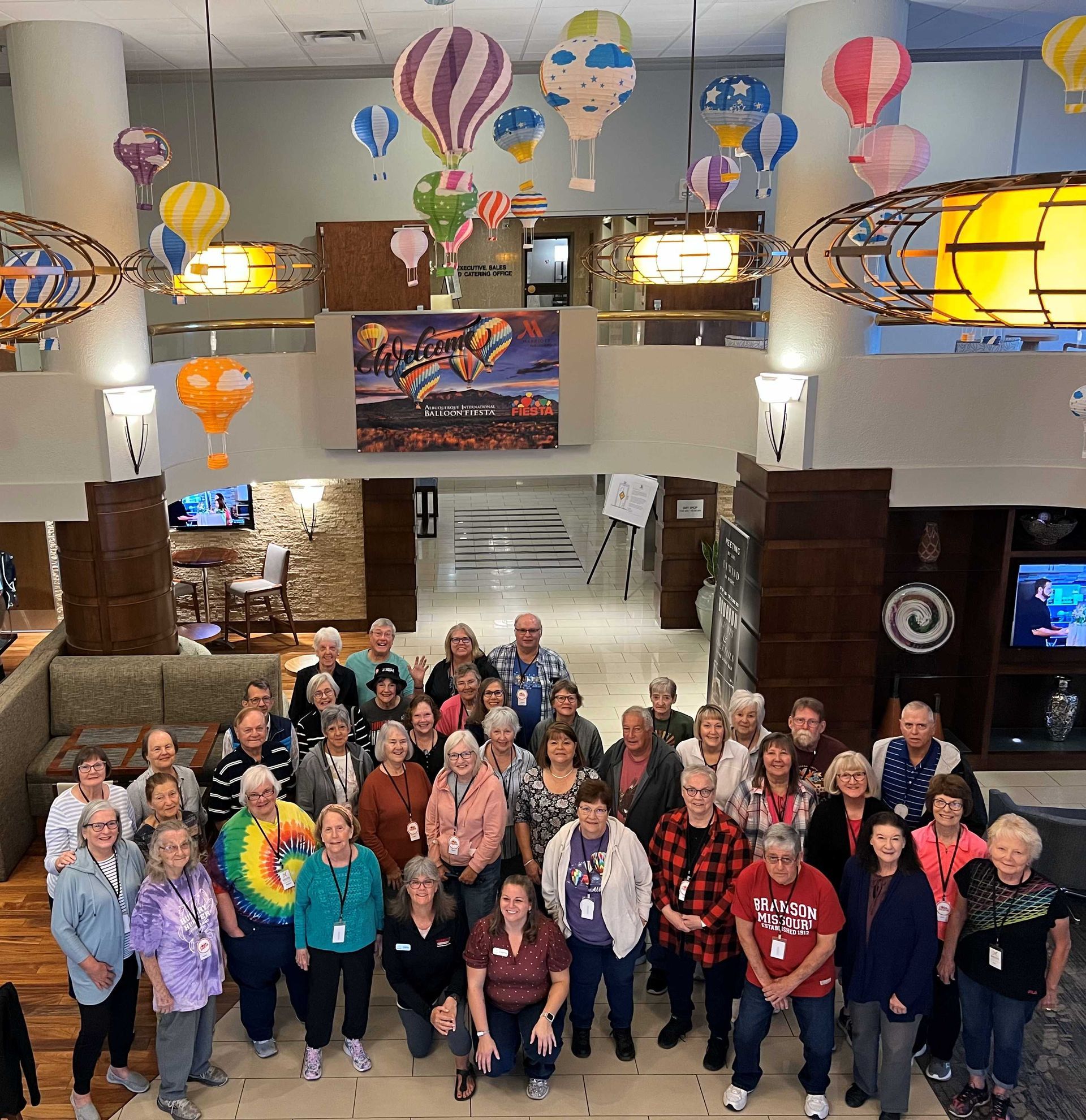 A large group of people are posing for a picture in a room with hot air balloons hanging from the ceiling
