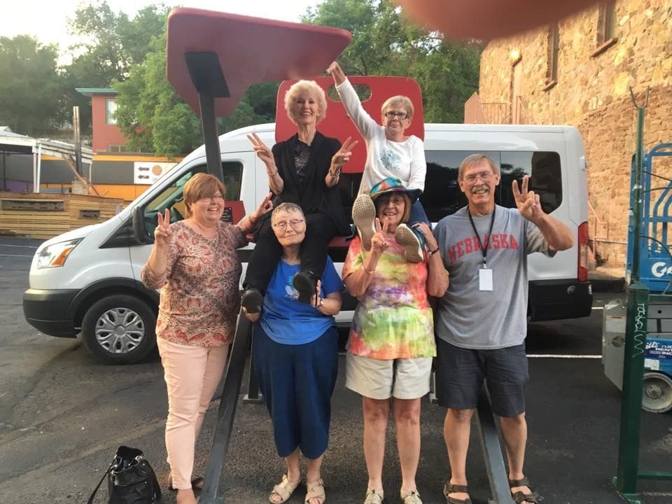 A group of people are posing for a picture in front of a van.